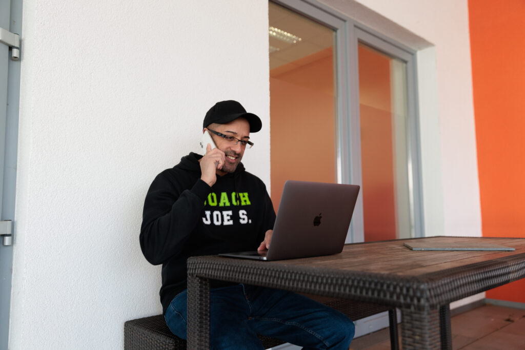 Mann sitzt am Tisch und telefoniert